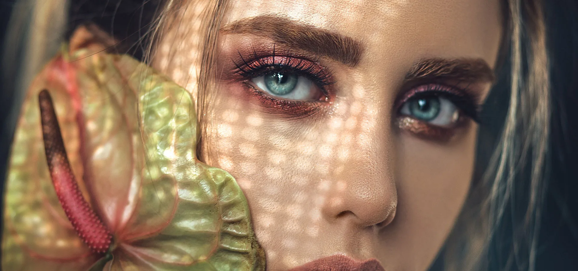 Editorial beauty portrait — dappled sunlight and anthurium bloom