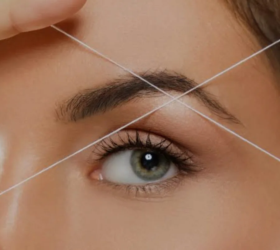 Threading — close-up of cotton thread across brow